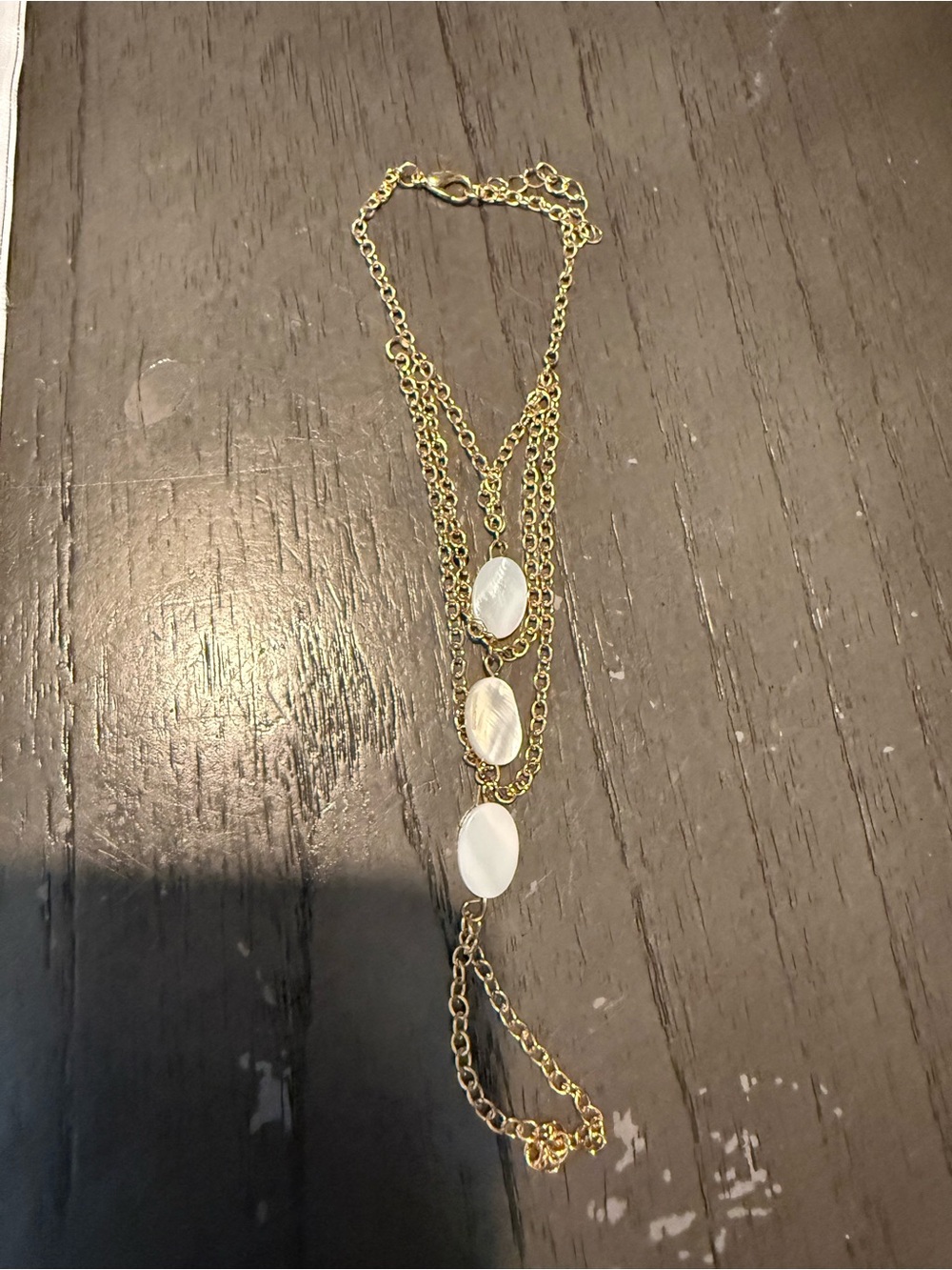 Gold tone layer hand chain bracelet with white shell stone details